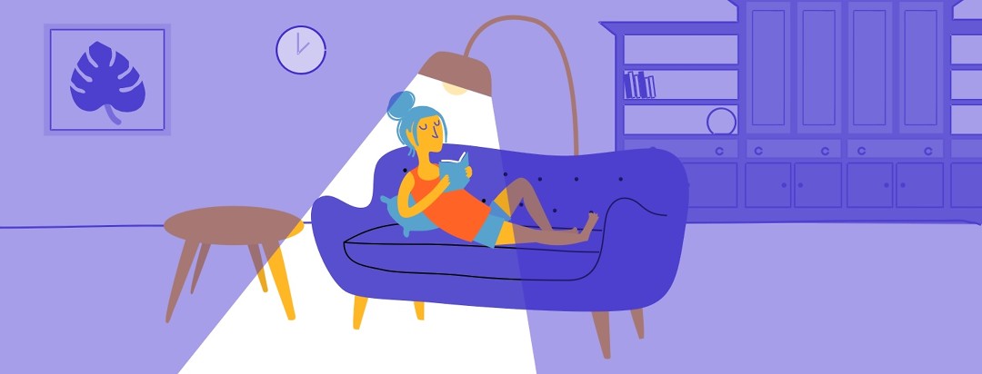 Image of woman sitting on the couch and reading at night.