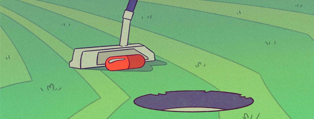 Putter on a golf green with a pill in lieu of a ball making an easy putt into the hole