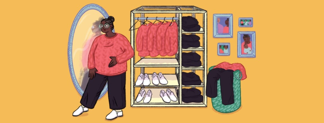 A woman wearing a pink sweater, black pants, and white slip on shoes is looking at herself in the mirror with the same outfit on hangers in the background